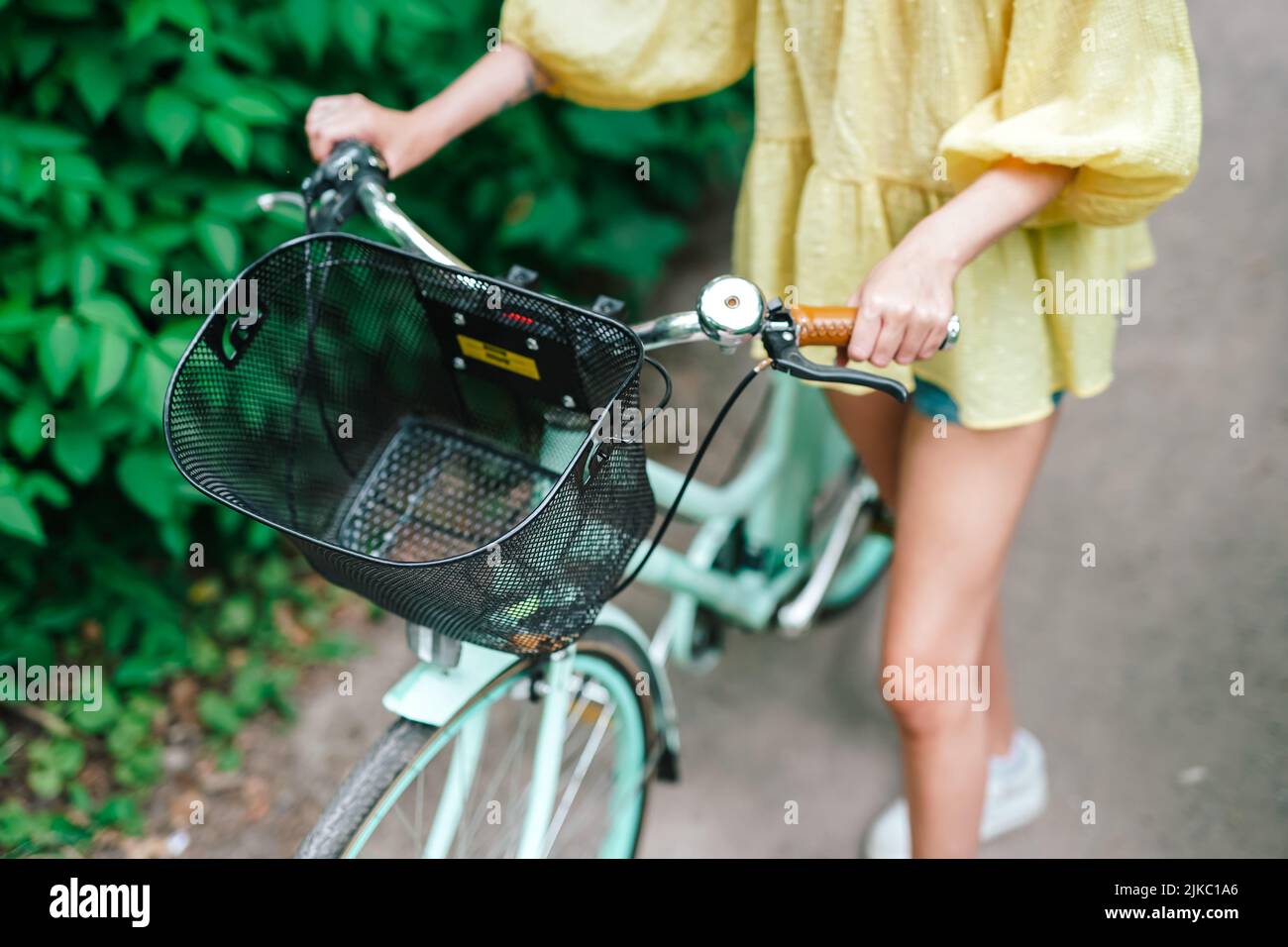 joven rubia a punto de montar una bicicleta en un sendero de verano fuera Foto de stock