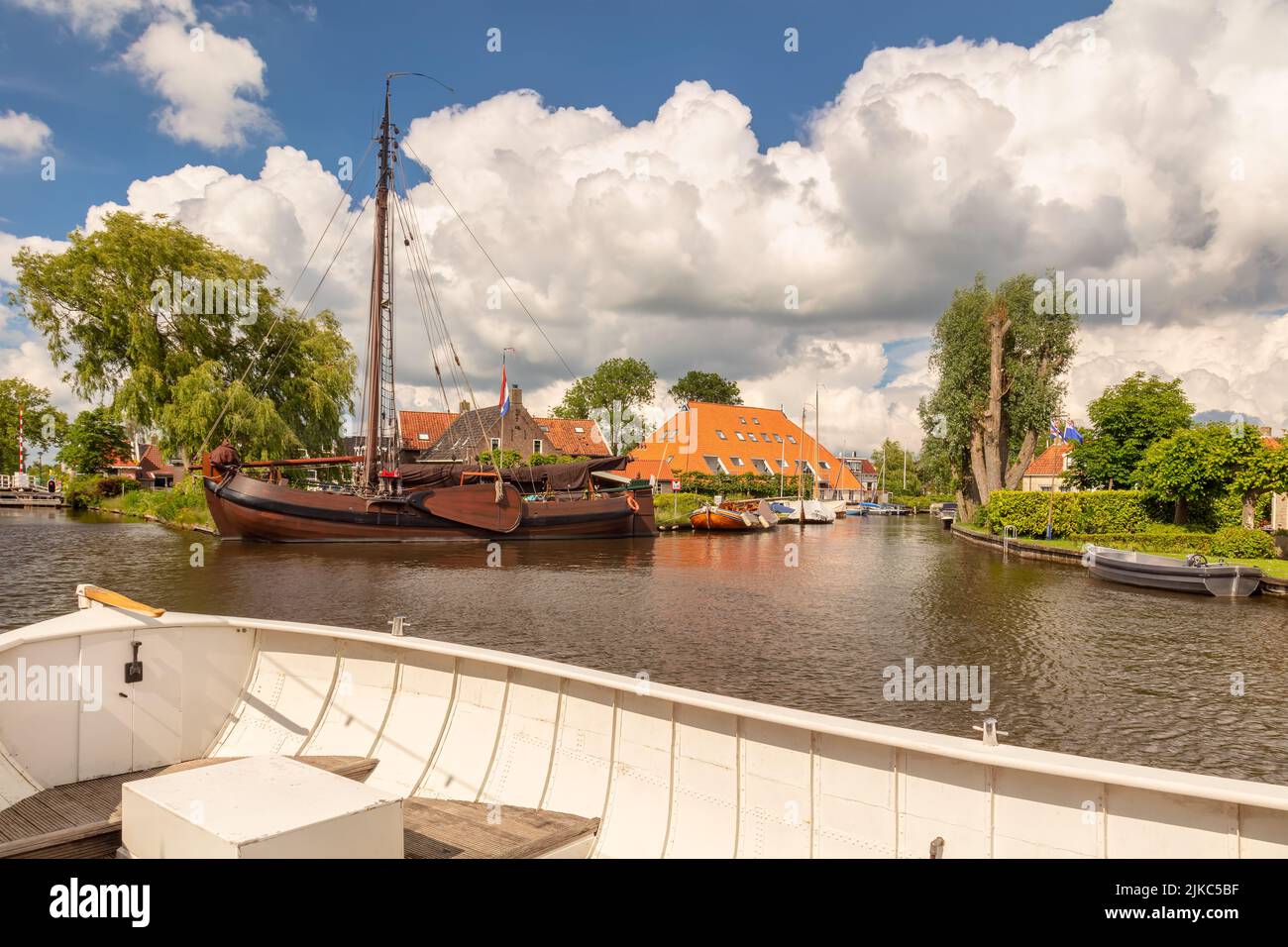 Sloop blanco delante de un viejo velero en un canal en el pueblo holandés de Heeg, Frisia, Países Bajos Foto de stock