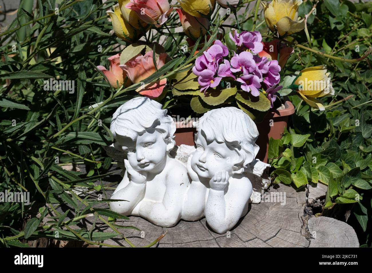 Arles, Francia. Lápida de cementerio, ángeles de piedra y flores de plástico. Foto de stock