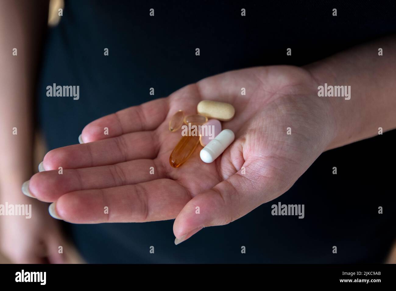 Mano sosteniendo muchas píldoras diferentes listas para tragar Foto de stock