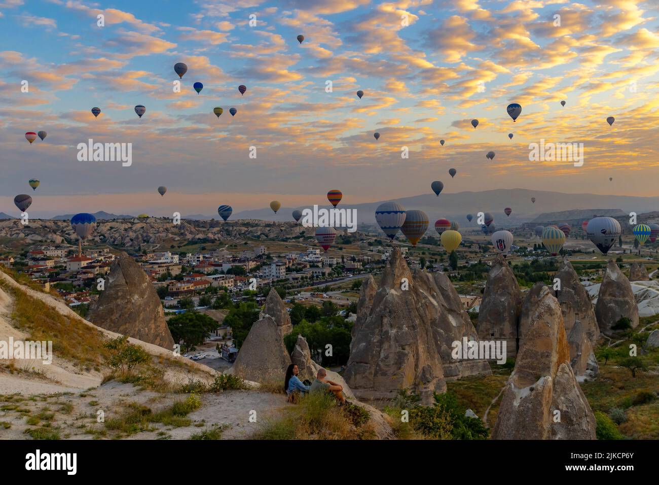 GOREME/TURQUÍA - 30 de junio de 2022: Los turistas ven el espectáculo de los globos de aire caliente volando sobre ellos al amanecer. Foto de stock