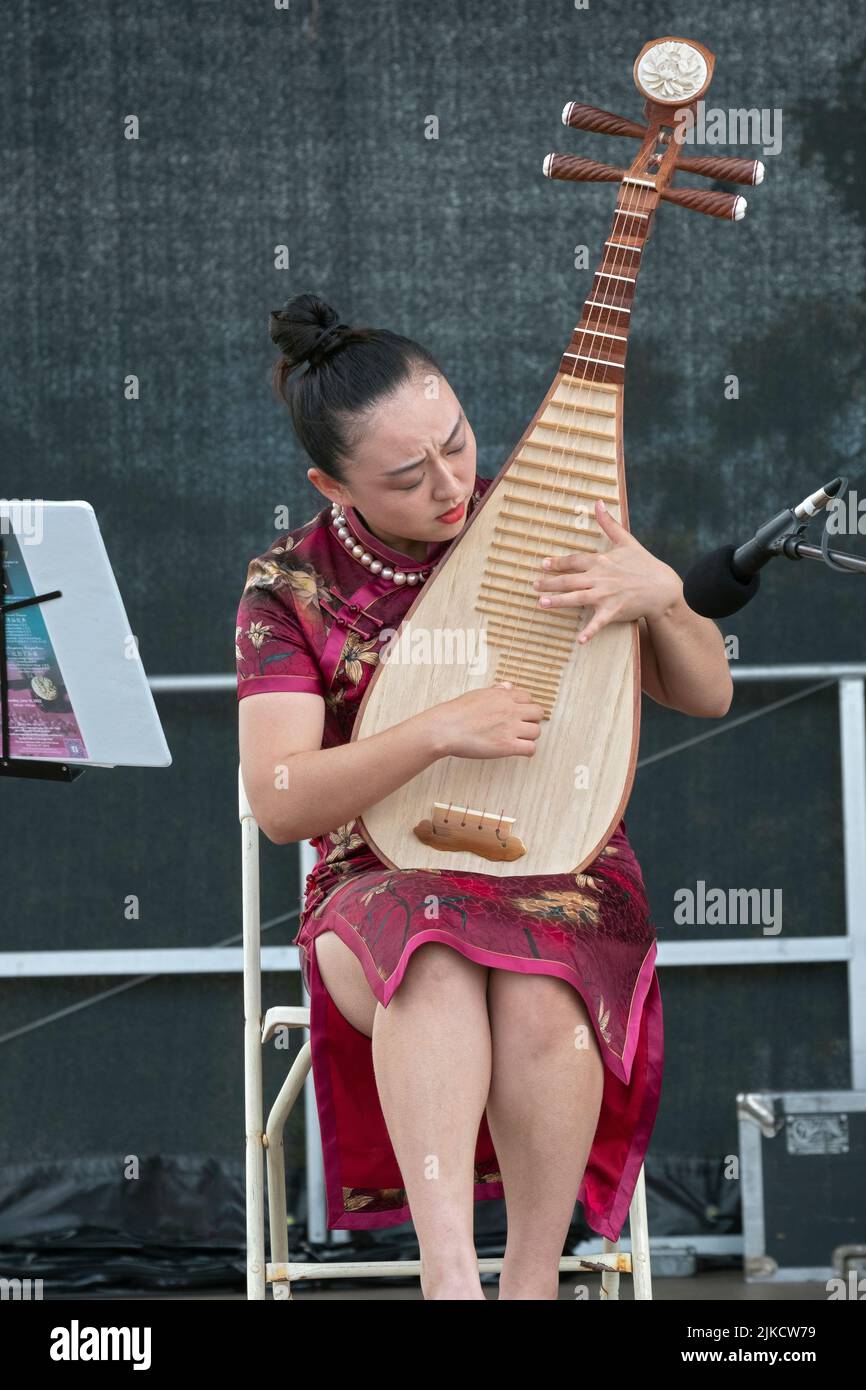 Un hermoso miembro del conjunto de música china de Nueva York toca la pipa, un instrumento chino tradicional. En el Festival del Dragón de Hong Kong Foto de stock