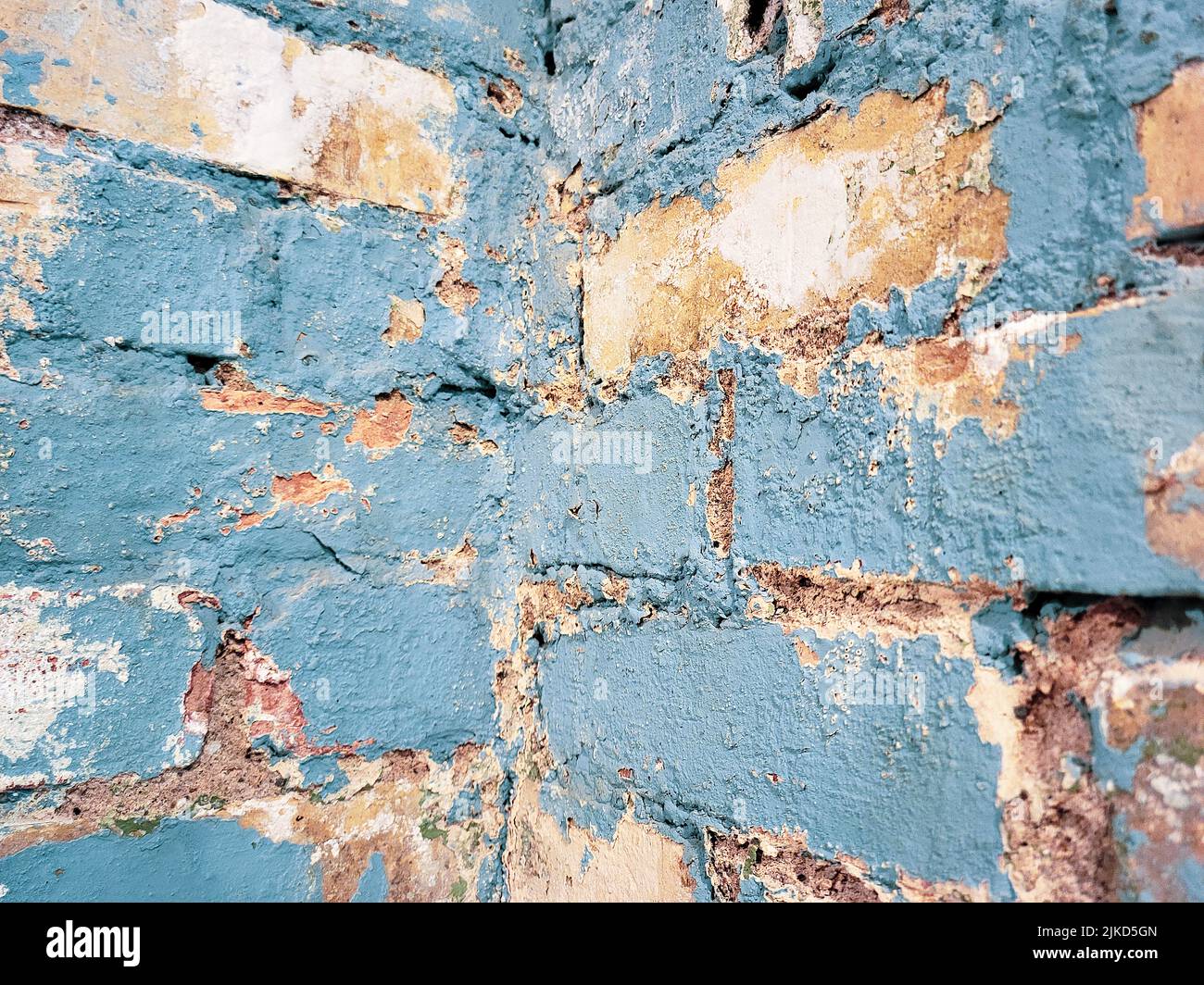 Cerca de pintura azul descolorida en la pared de ladrillo de la esquina Foto de stock