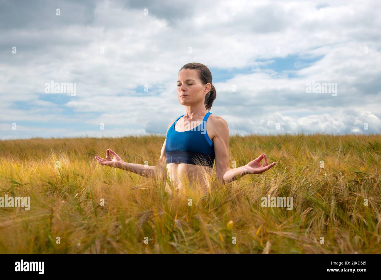 Mujer atractiva meditando y practicando yoga en un campo. Foto de stock