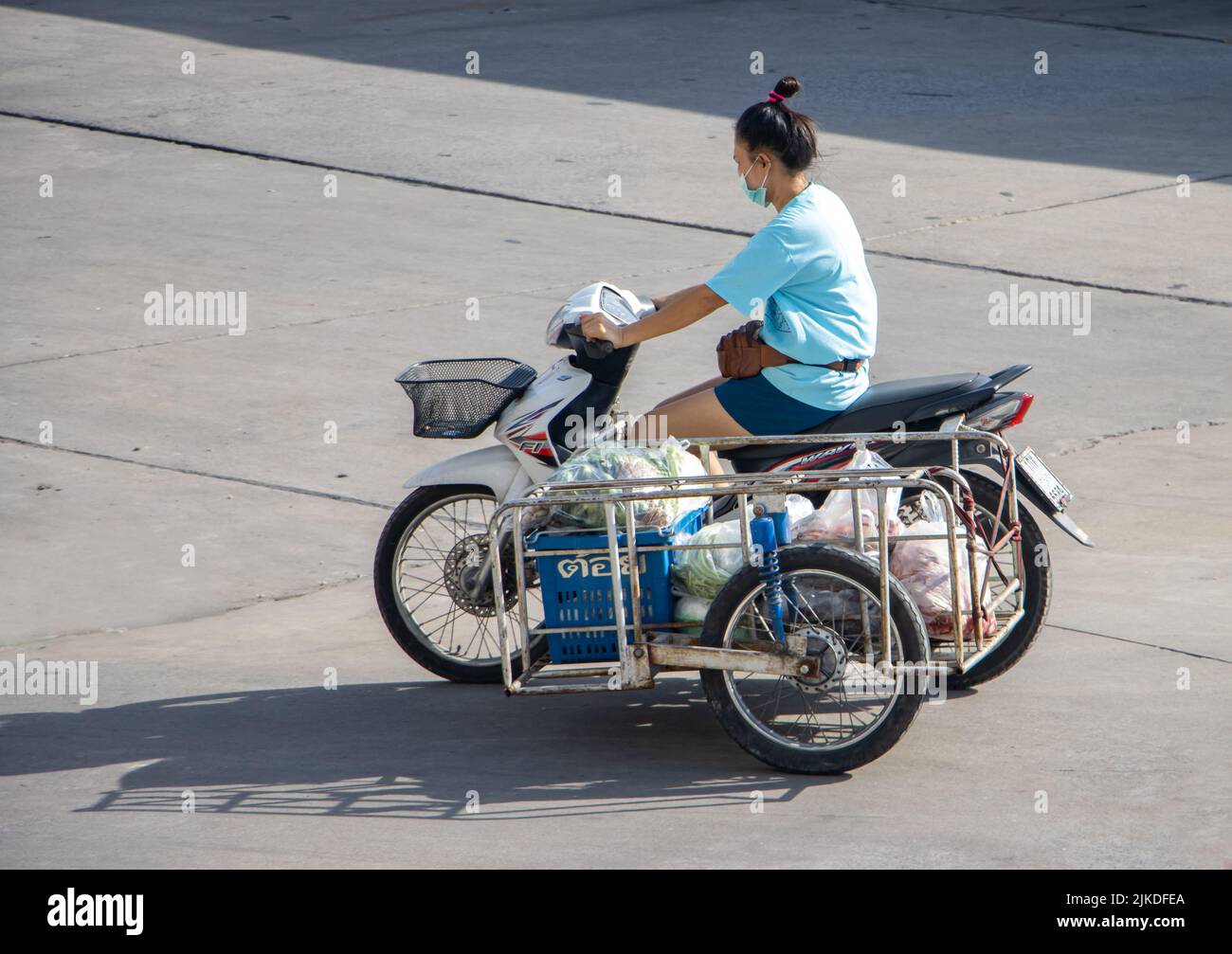 SAMUT PRAKAN, TAILANDIA, 30 2022 DE MAYO, Una mujer transporta alimentos frescos crudos en un carro en una moto Foto de stock
