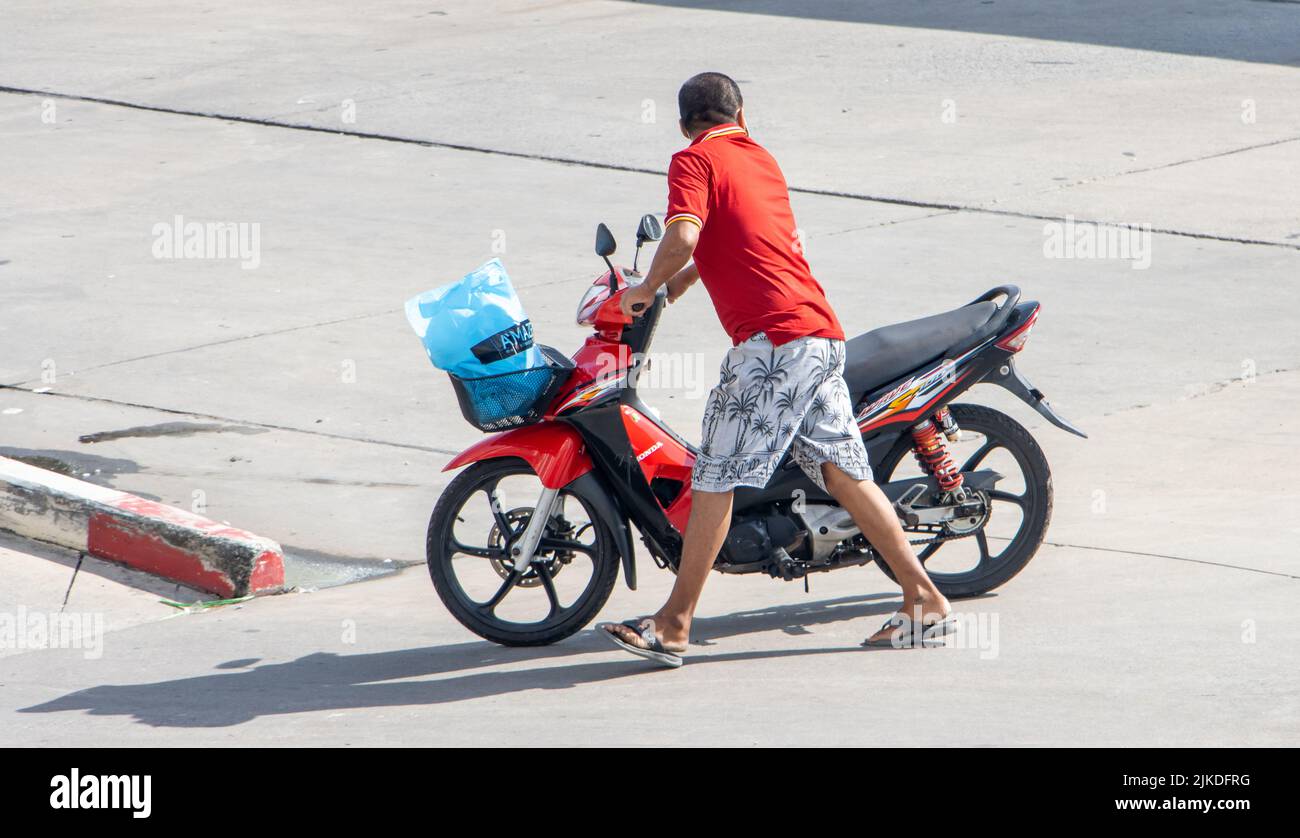 SAMUT PRAKAN, TAILANDIA, 30 2022 DE MAYO, Un hombre empuja una motocicleta que no puede circular por la calle Foto de stock