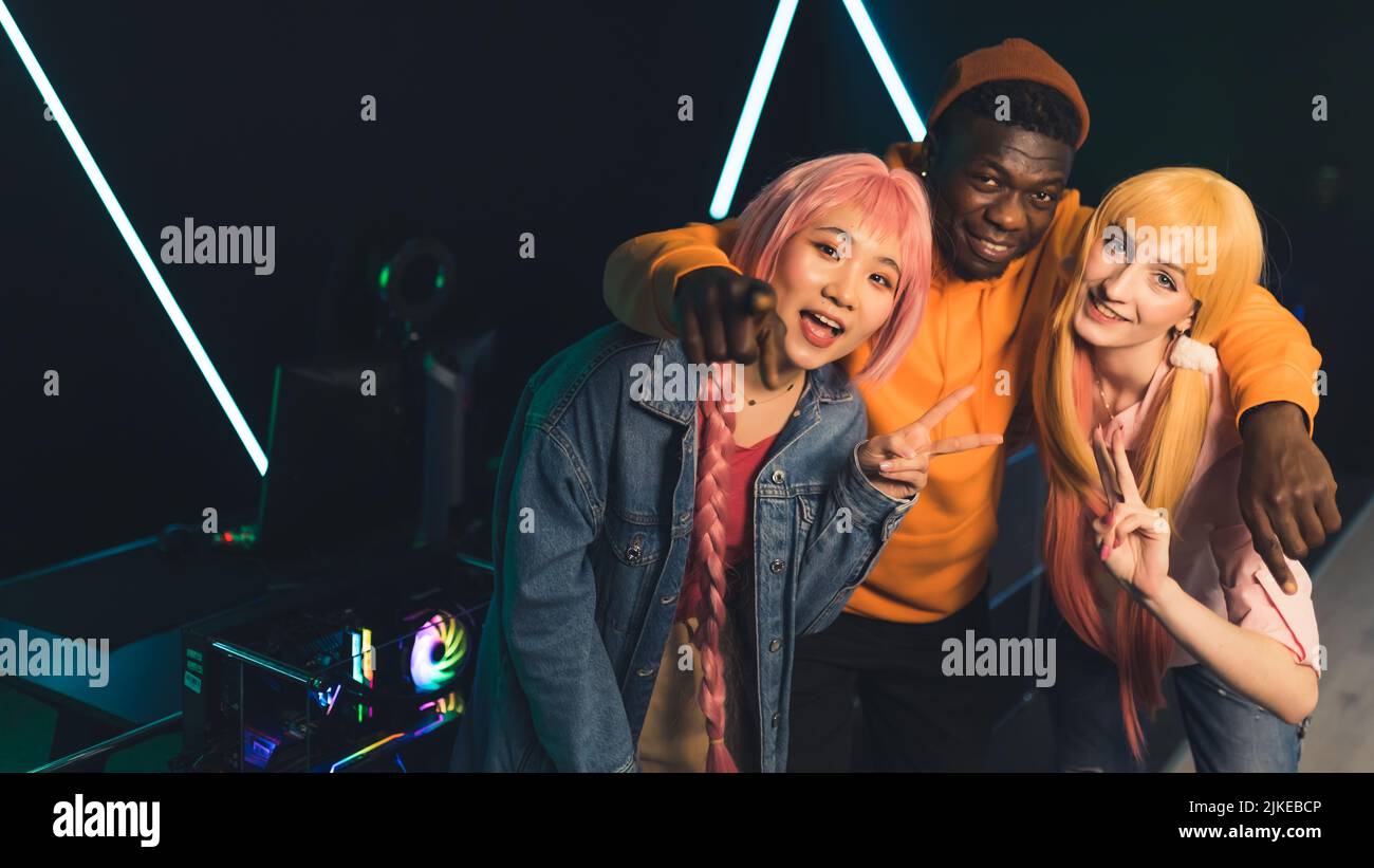 Jugadores adolescentes con ropa de colores posando para hacer fotos delante de un juego profesional sonriendo mostrando señales de paz. Foto de grupo. Fotografía de alta calidad Foto de stock