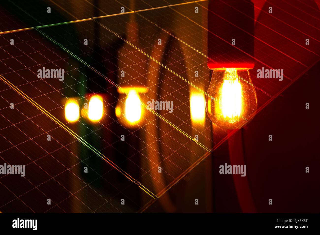 detalle de varias bombillas encendidas en color amarillo y tono cálido, fondo oscuro - placas con células para la captura de la energía solar Foto de stock