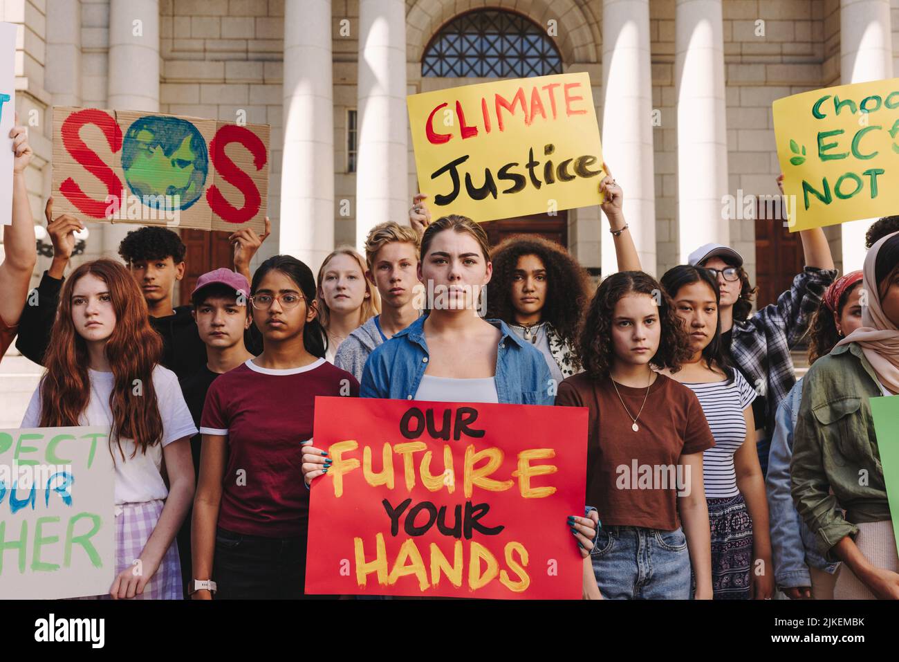 Adolescentes multiculturales que realizan una protesta por el cambio climático en la ciudad. Grupo de jóvenes activistas sosteniendo pancartas y pancartas mientras marchaba por el clima Foto de stock