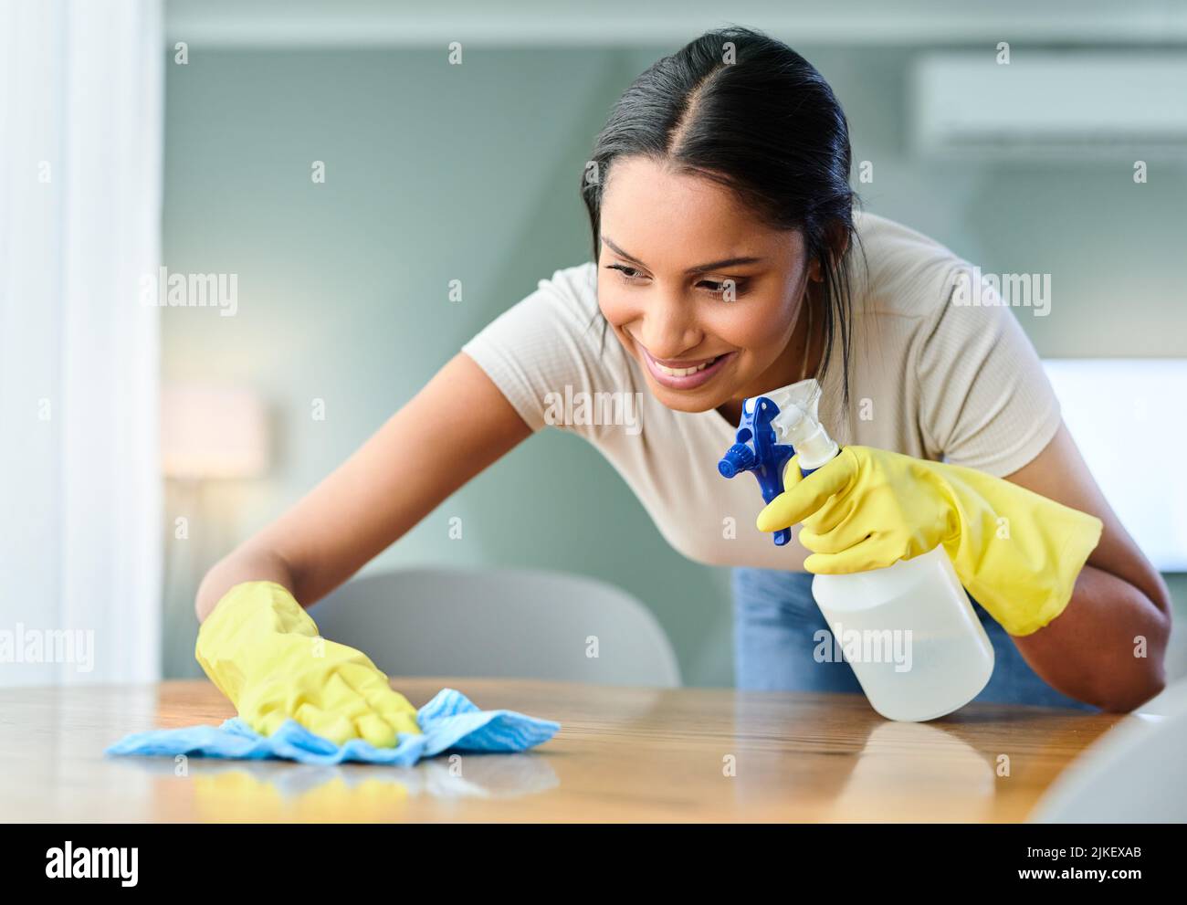 Una mujer joven limpia una superficie en casa. Foto de stock
