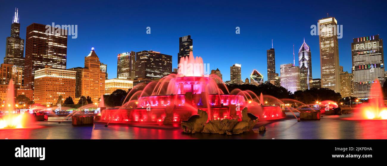 El horizonte de Chicago iluminado al atardecer con la colorida fuente de Buckingham en primer plano, Illinois, EE.UU Foto de stock