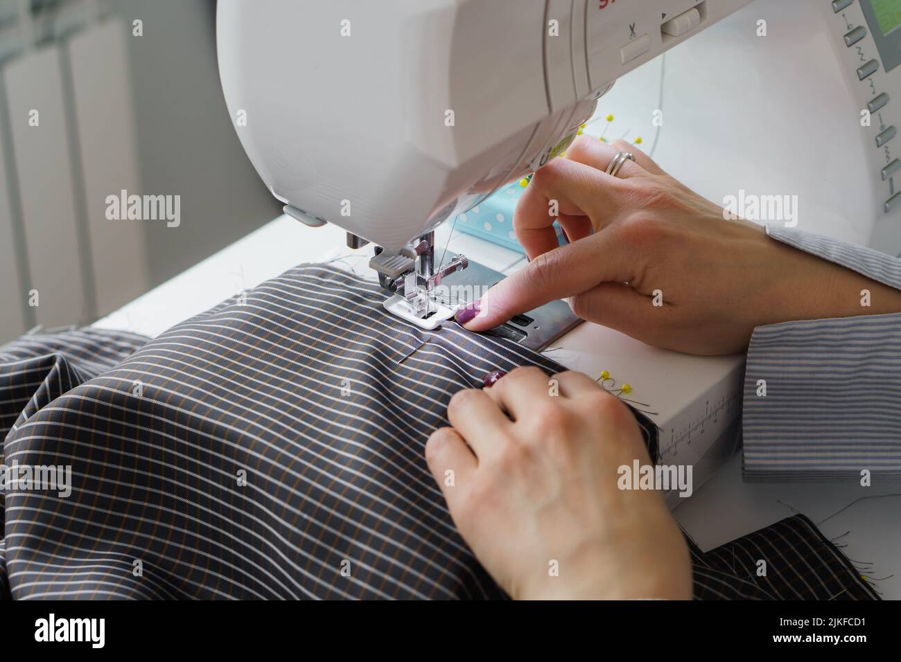 Mujer costurera trabaja en máquina de coser. Las manos del fabricante de tocadores trabajan en la fábrica de costura Foto de stock