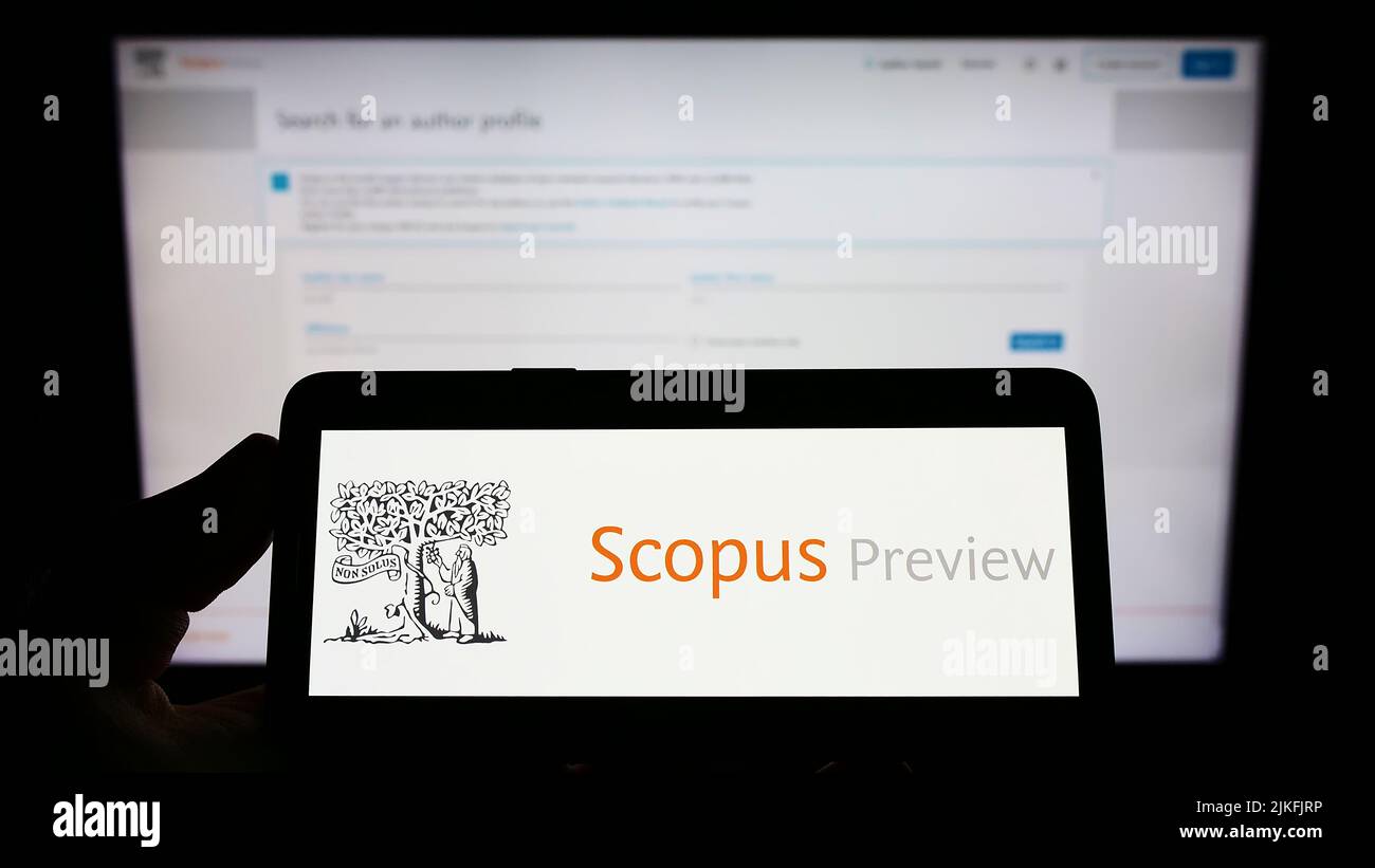 Persona con smartphone con el logotipo de la base de datos de citas Scopus Preview en pantalla delante del sitio web. Enfoque la pantalla del teléfono. Foto de stock
