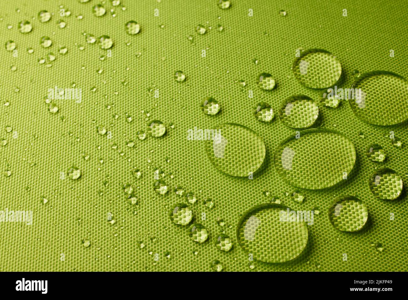 Vista superior Textil verde abstracto con primer plano transparente pequeñas gotas de agua sobre tejido laminado impermeable húmedo en habitación luminosa Foto de stock