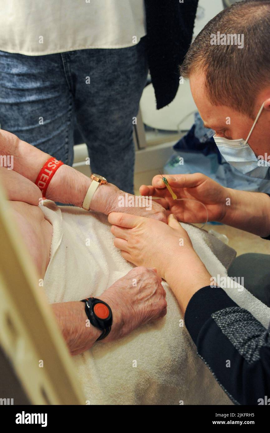 Enfermera privada que realiza un análisis de sangre y una inyección de insulina en un paciente de 87 años de edad durante el baño. Paciente con un brazalete de alarma remota en la muñeca. Foto de stock