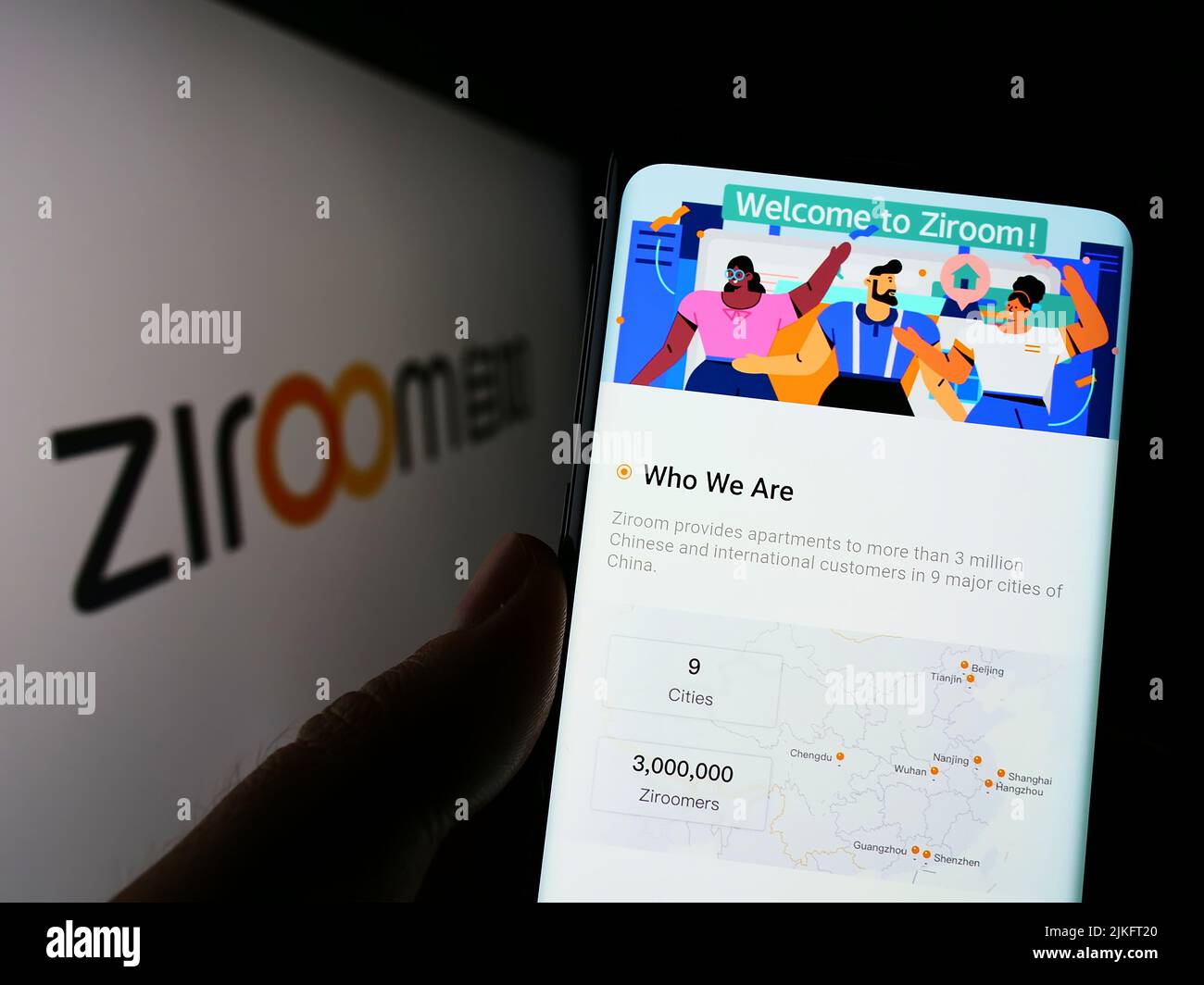 Persona que sostiene el teléfono móvil con el Web site de la compañía inmobiliaria china Ziroom en la pantalla delante del logotipo del negocio. Enfoque en el centro de la pantalla del teléfono. Foto de stock
