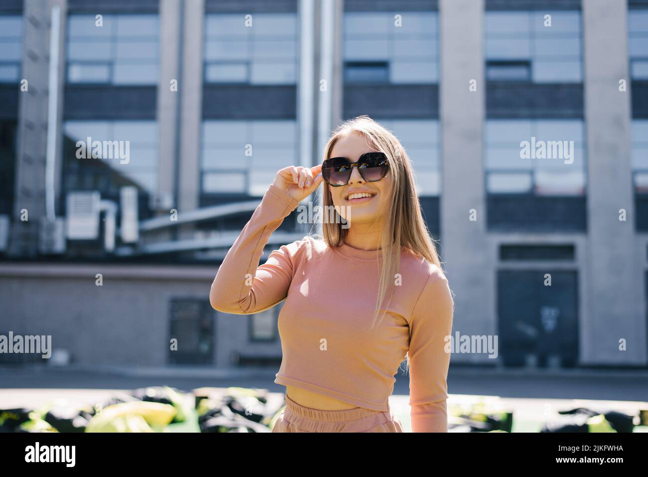 Retrato de una mujer sonriente feliz con gafas de sol en la ciudad en verano Foto de stock