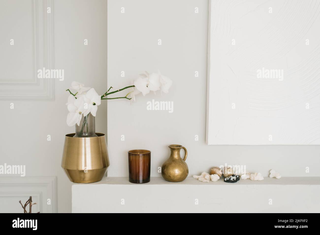 Elegante decoración de la sala de estar en un estilo minimalista. Un jarrón con orquídeas blancas y varios contenedores Foto de stock