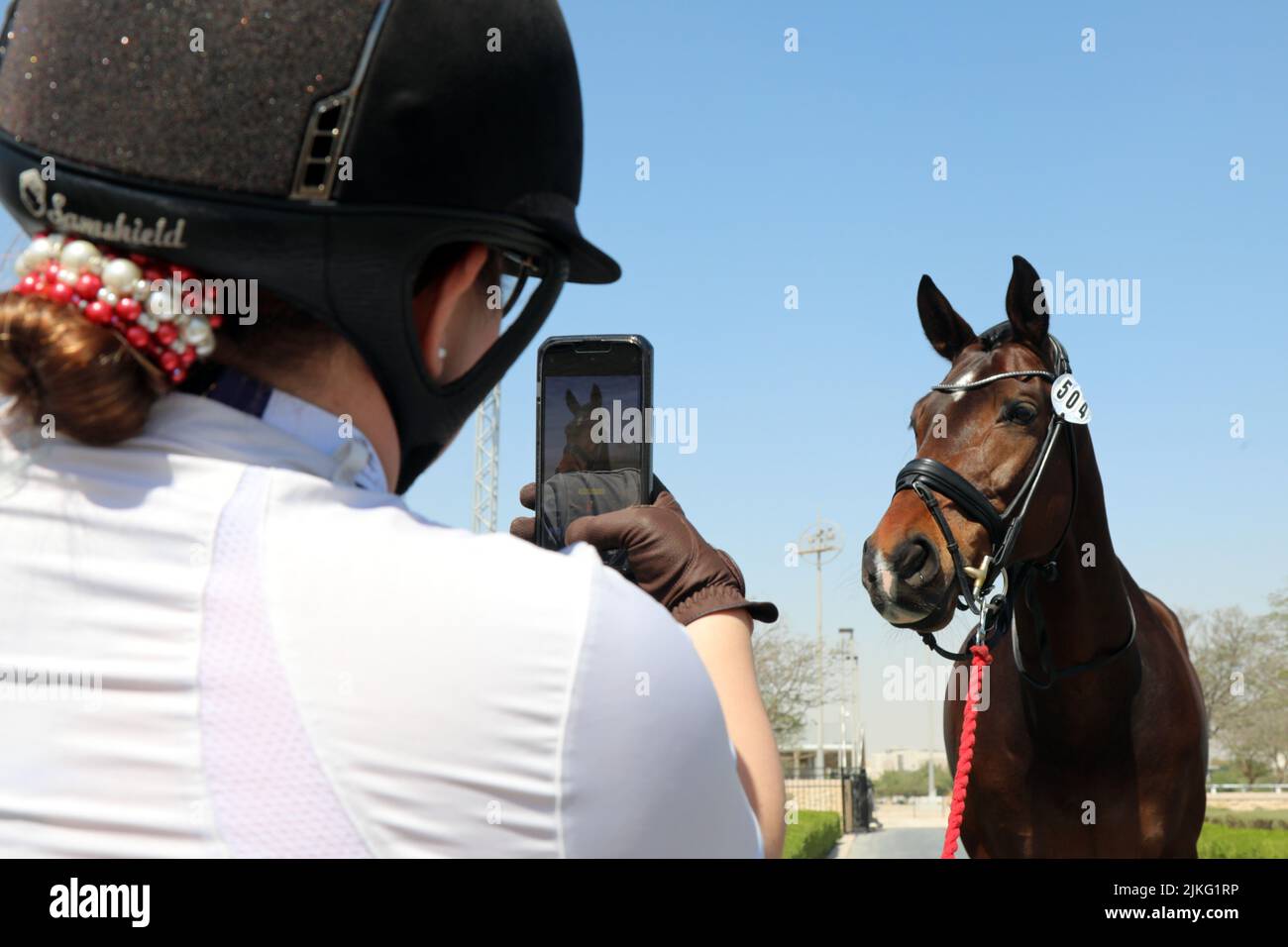 24.02.2022, Qatar, , Doha - Rider Tomando fotos de su caballo con su teléfono celular en un espectáculo de caballos. 00S220224D156CAROEX.JPG [VERSIÓN DE MODELO: NO, CORRECTA Foto de stock