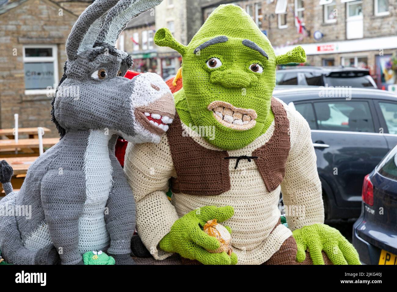 Hawes Village en los Yorkshire Dales, personajes Shrek de punto de tamaño natural expuestos para recaudar fondos benéficos fuera del Board Inn, Yorkshire, Inglaterra Foto de stock