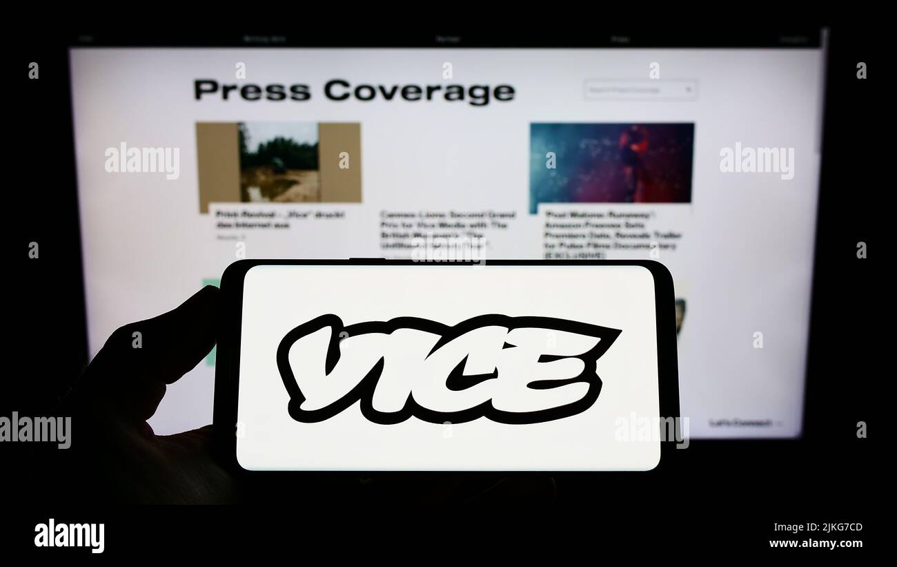 Persona que sostiene un smartphone con el logotipo de la compañía de radiodifusión Vice Media LLC en la pantalla delante del sitio web. Enfoque la pantalla del teléfono. Foto de stock