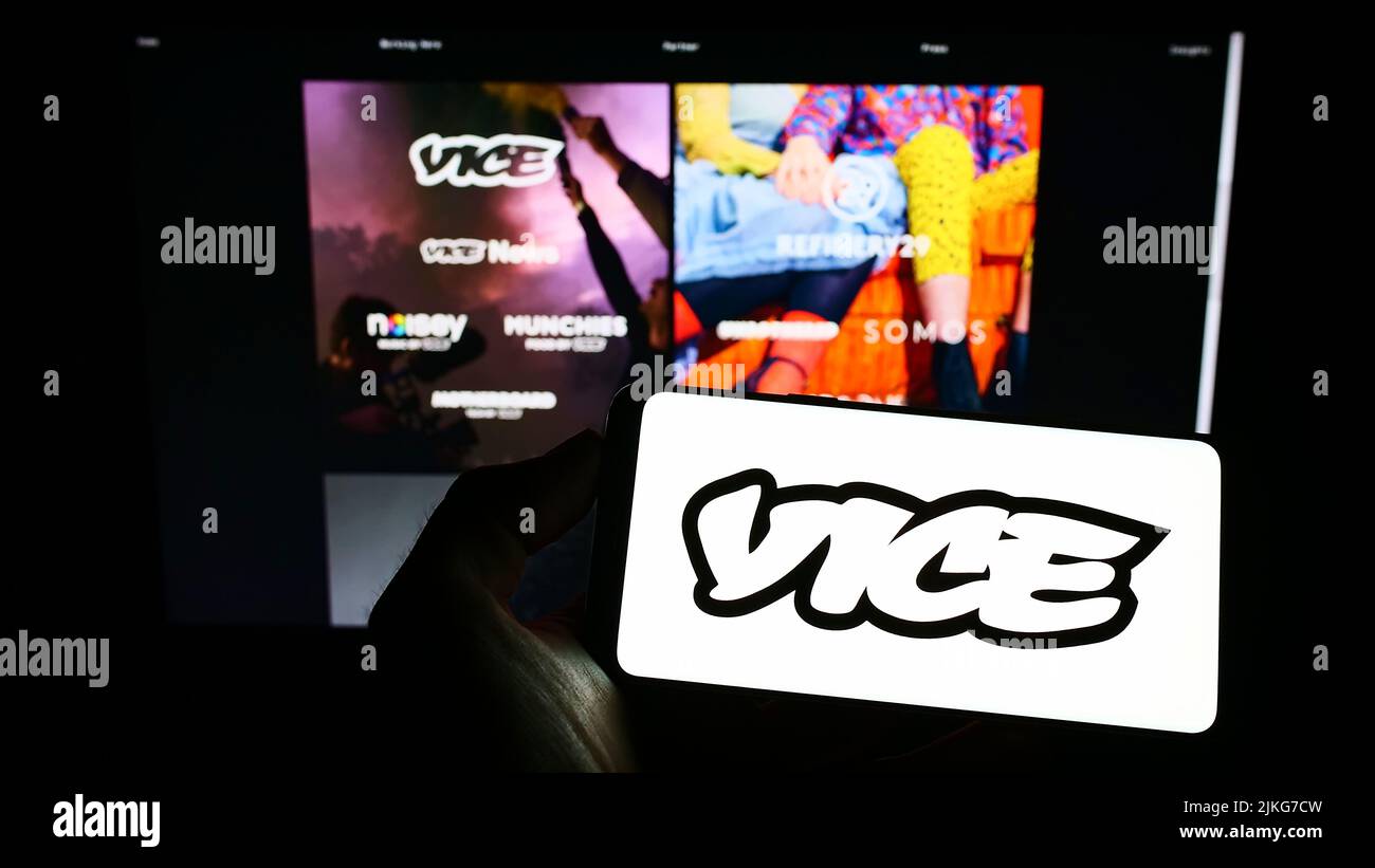 Persona que sostiene el teléfono móvil con el logotipo de la compañía de radiodifusión Vice Media LLC en la pantalla delante de la página web del negocio. Enfoque la pantalla del teléfono. Foto de stock
