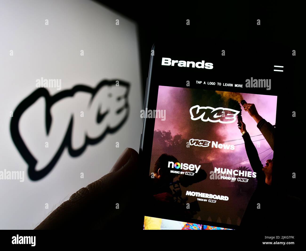Persona que sostiene el teléfono celular con el Web site de la compañía de radiodifusión Vice Media LLC en la pantalla delante del logotipo. Enfoque en el centro de la pantalla del teléfono. Foto de stock