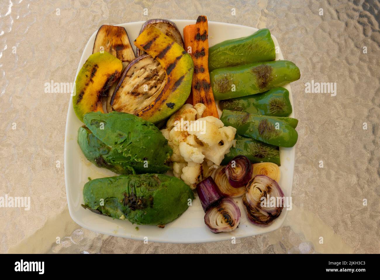 Plato de verduras orgánicas a la parrilla, con pimienta, cebolla, zanahoria, coliflor, calabaza, berenjena y aguacate. Comida sana y sabrosa. Comida vegetariana Foto de stock