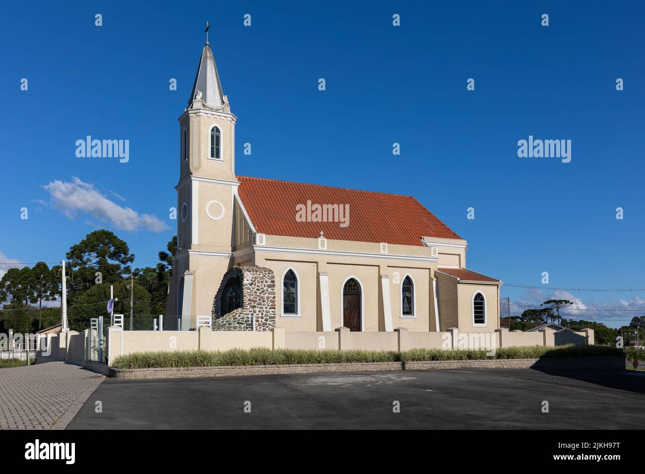 Una vista panorámica de una iglesia católica contra un cielo azul sin nubes Foto de stock