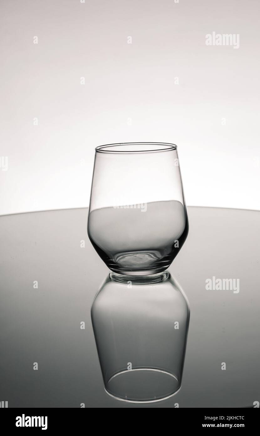 Toma en escala de grises de una copa de cristal vacía con reflejo en