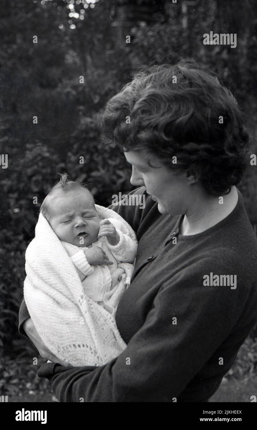 1960s, histórica, afuera, una madre sosteniendo en sus brazos a su nuevo bebé, Inglaterra, Reino Unido. Foto de stock