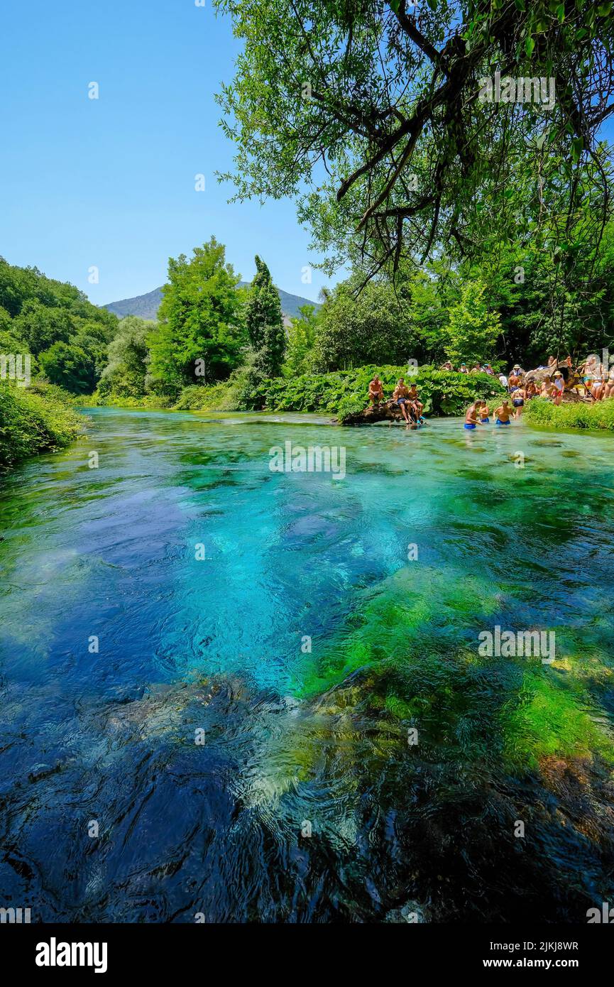 Muzina, Albania - Los turistas se bañan en Syri i Kaltër, EL OJO AZUL es la fuente de agua más abundante del país con 6 ö³/s, situada a medio camino entre las ciudades más grandes de Saranda en la costa y Gjirokastra tierra adentro. Foto de stock