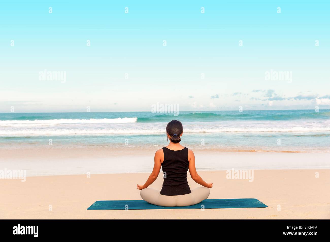 Mujer que practica yoga en la orilla del mar de la playa tropical, deporte dama de pie en la playa hacer ejercicios de yoga. Foto de stock
