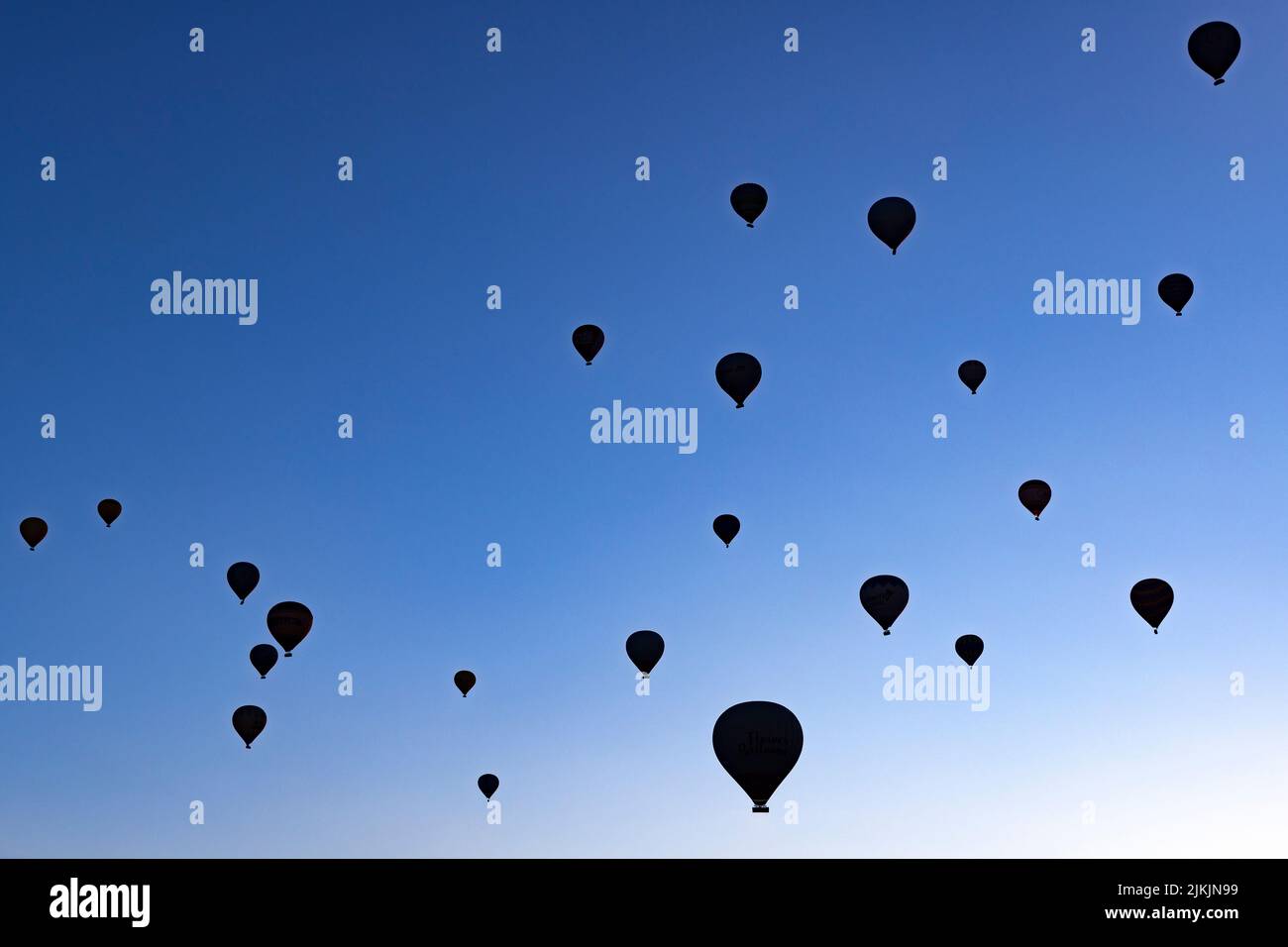 siluetas de globos de aire caliente que se elevan en el cielo azul Foto de stock