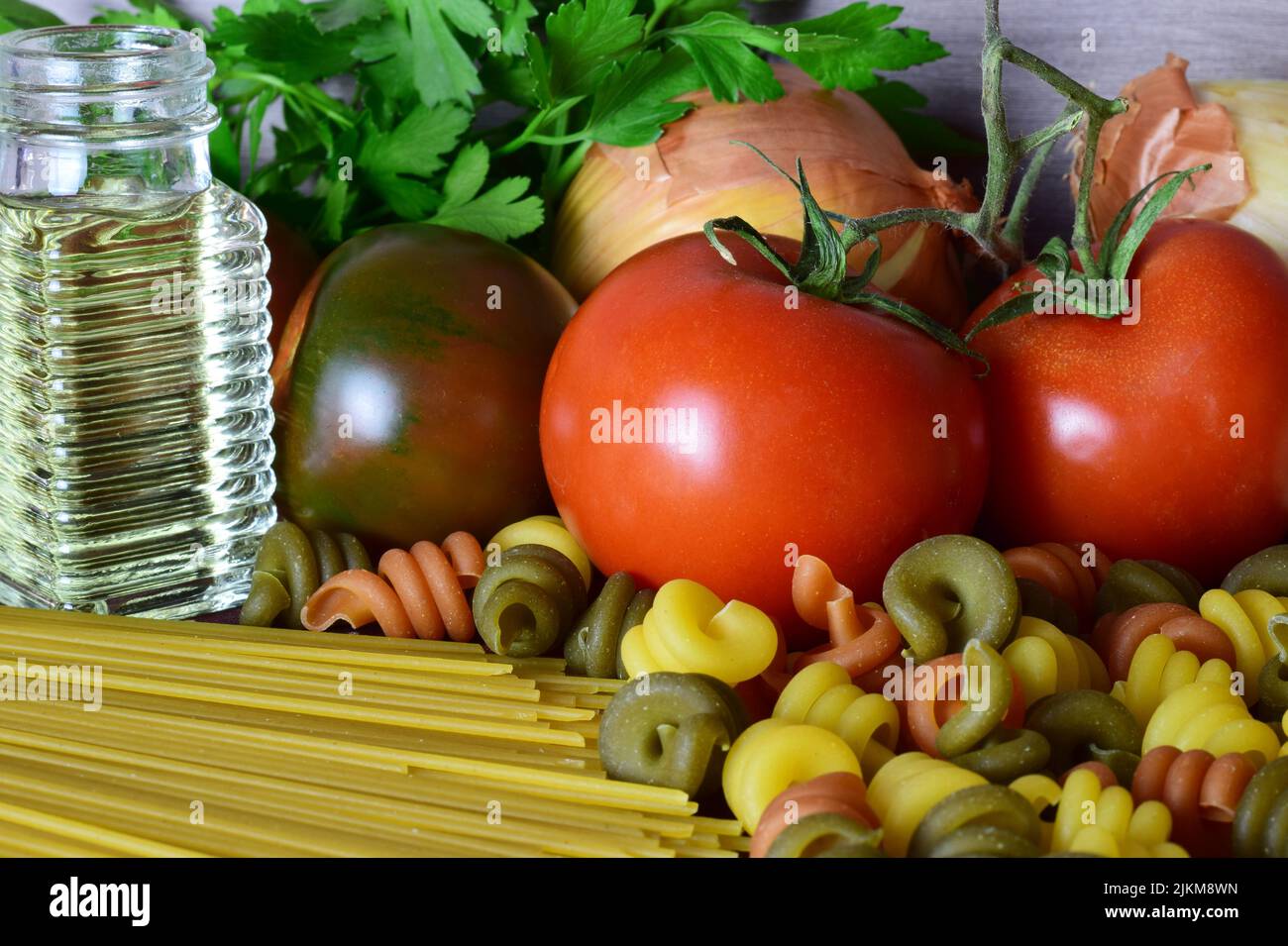 Un primer plano de colorida pasta cruda con deliciosos vegetales frescos junto a ellos Foto de stock