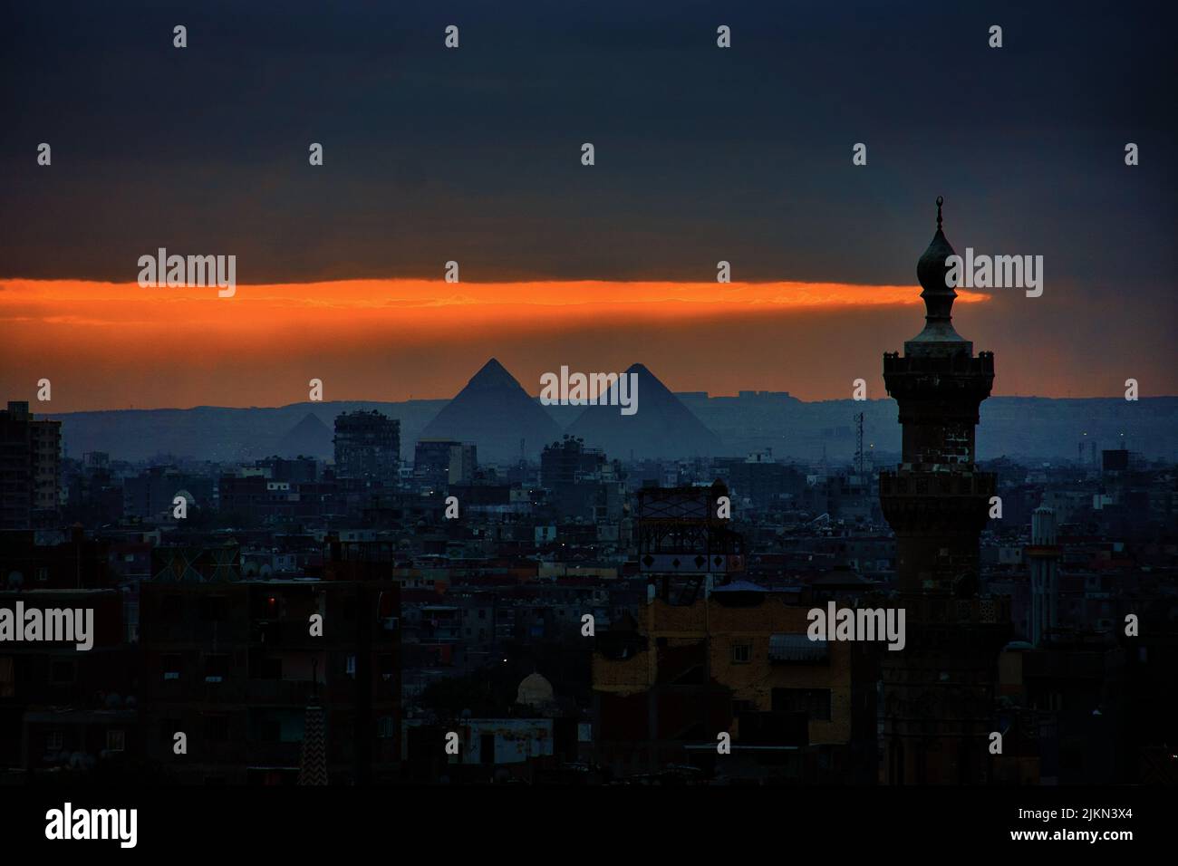 El paisaje urbano de El Cairo con los edificios y las pirámides en la puesta de sol escénica en Egipto Foto de stock