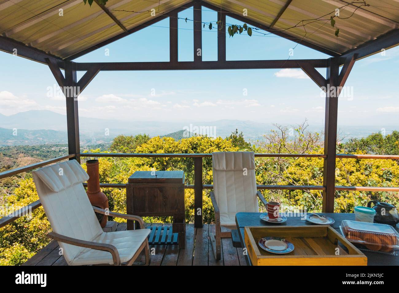 Sillas y café en un balcón en una pequeña finca en las montañas cerca de Talnique, El Salvador Foto de stock