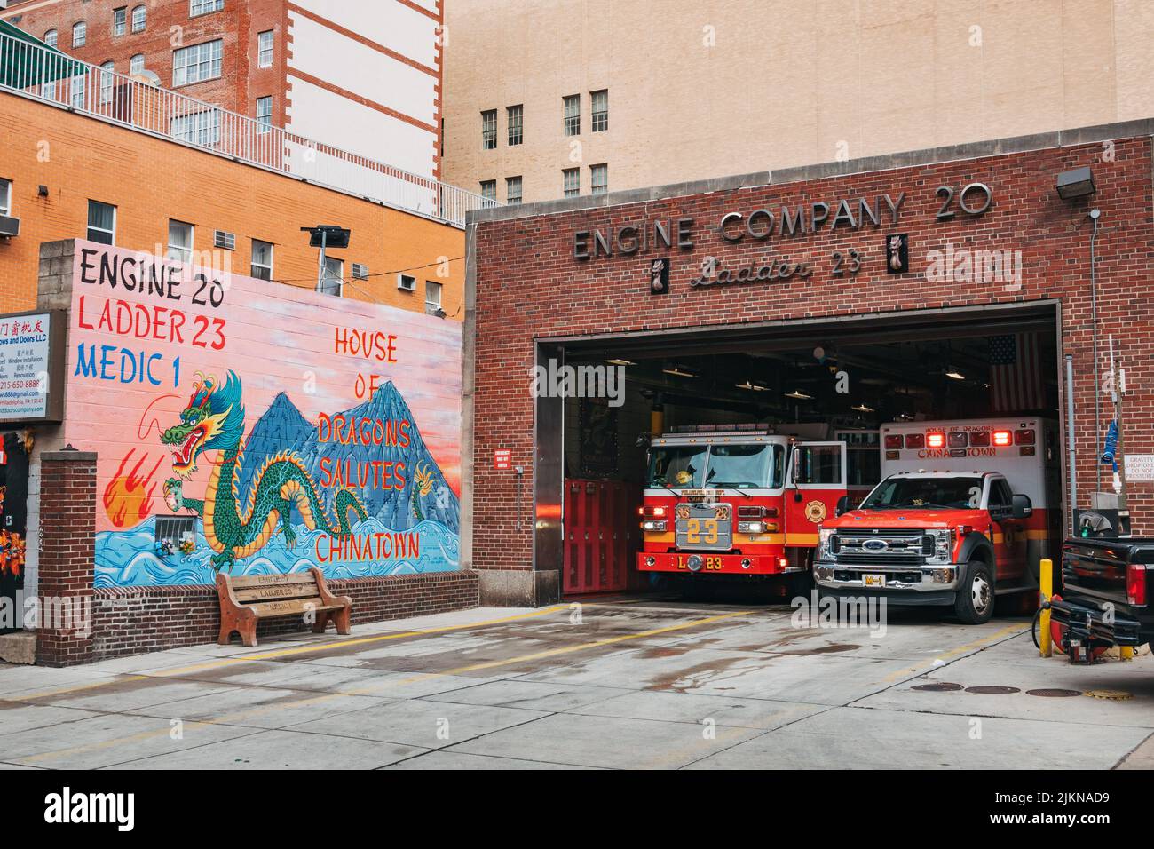 Un camión de bomberos y una ambulancia en el fuego de Engine Company 20 en Chinatown, Filadelfia. Un mural de dragón está pintado en la pared de frente Foto de stock