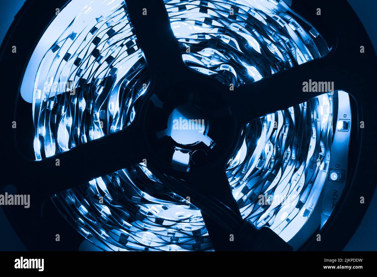 Tira de LED enrollada con luces azules que brillan en la oscuridad, foto de primer plano con enfoque selectivo Foto de stock