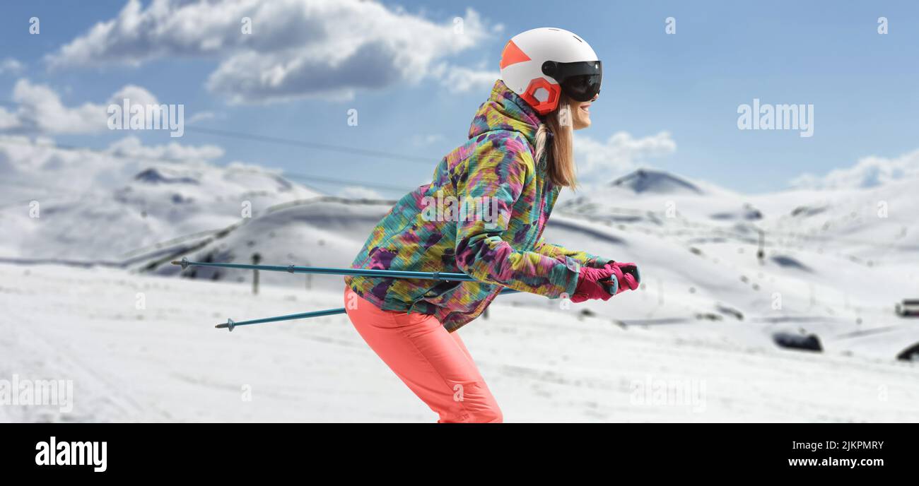 Foto de perfil de una mujer con casco esquiando en una montaña Foto de stock