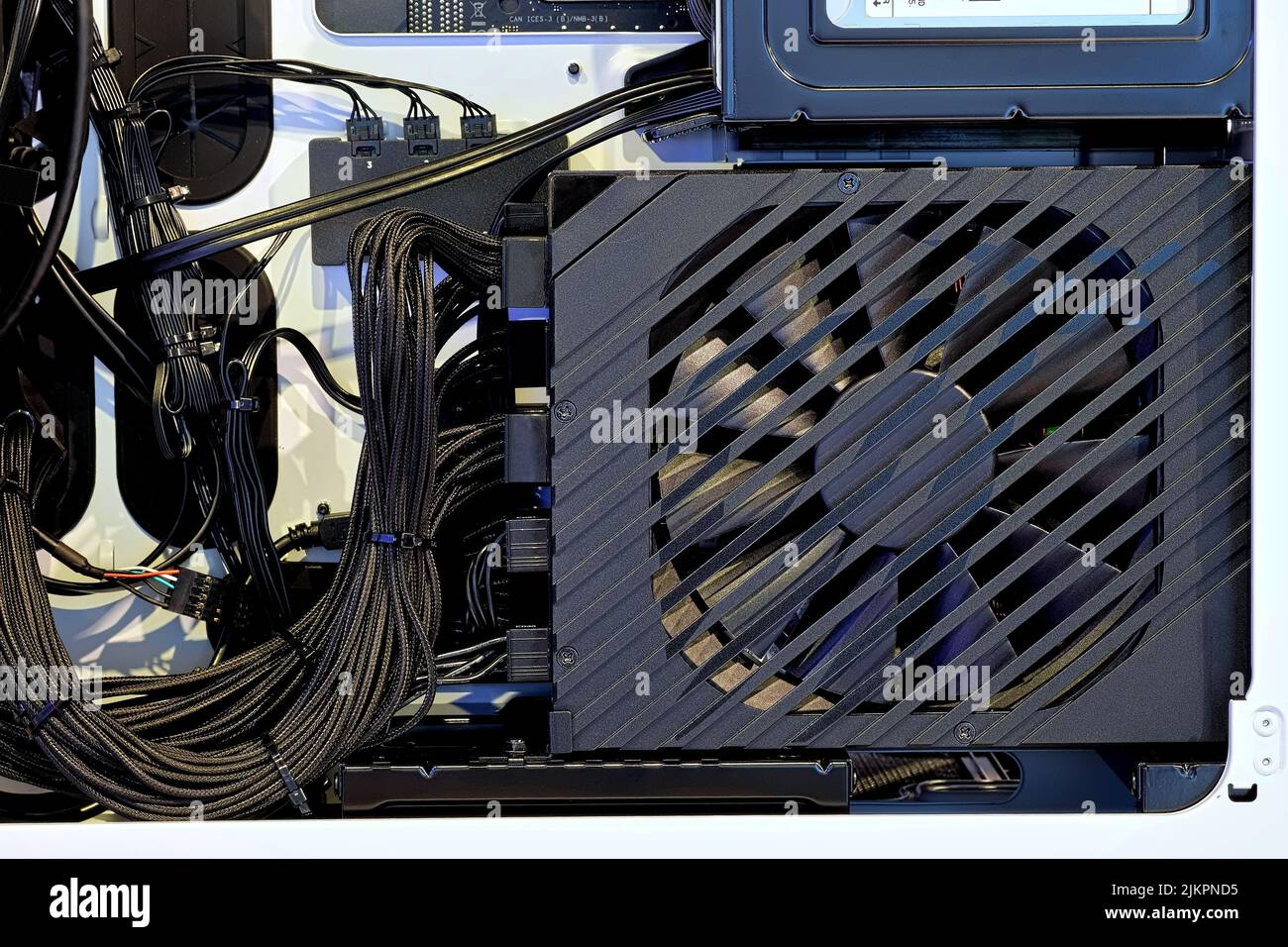 Primer plano y dentro de PC de sobremesa de alto rendimiento con unidad de fuente de alimentación, almacenamiento SSD y gestión de cables cableados en un interior ordenado en la carcasa del PC Foto de stock