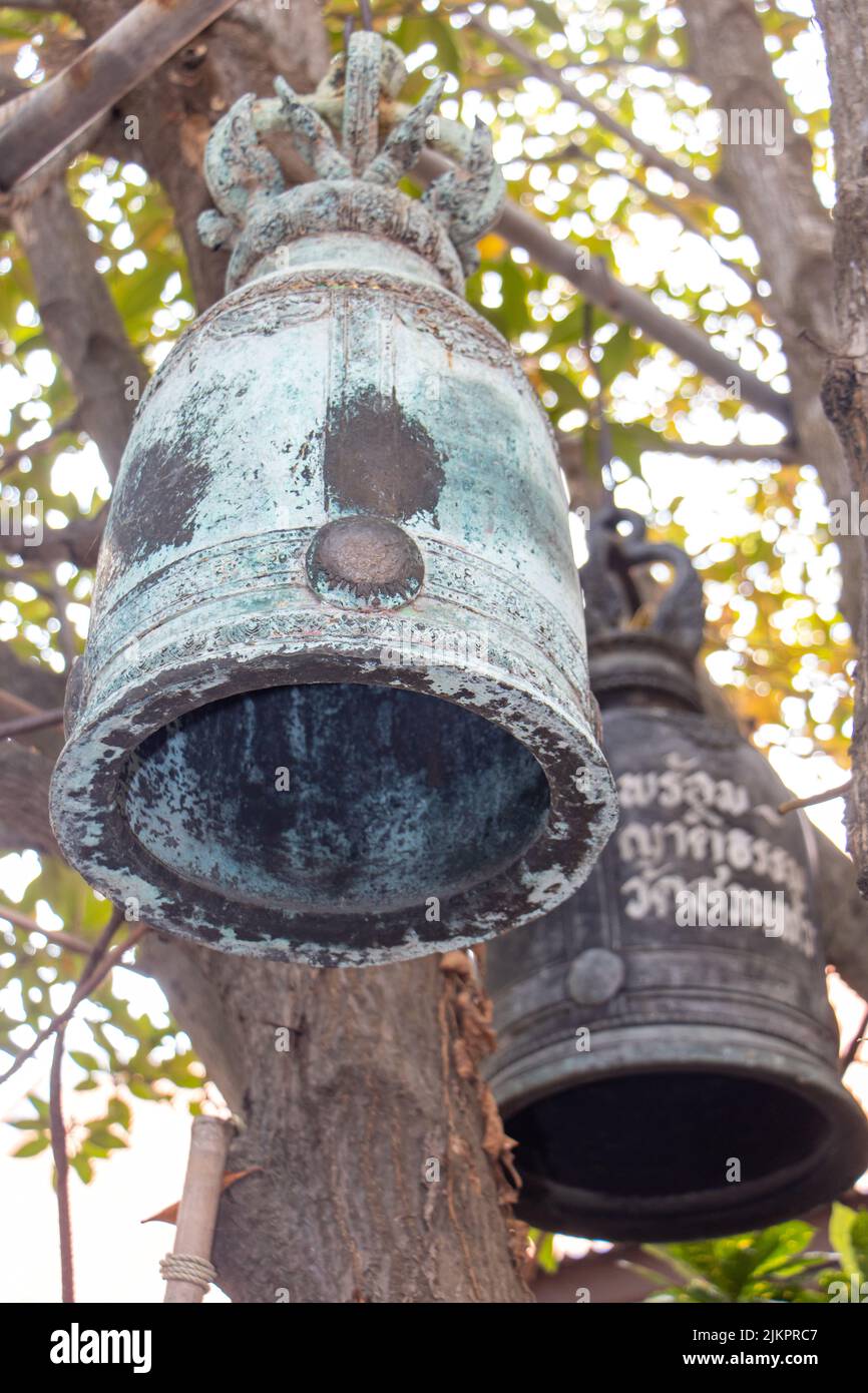 Un par de campanas colgando de una construcción en un árbol en un templo budista, Tailandia Foto de stock