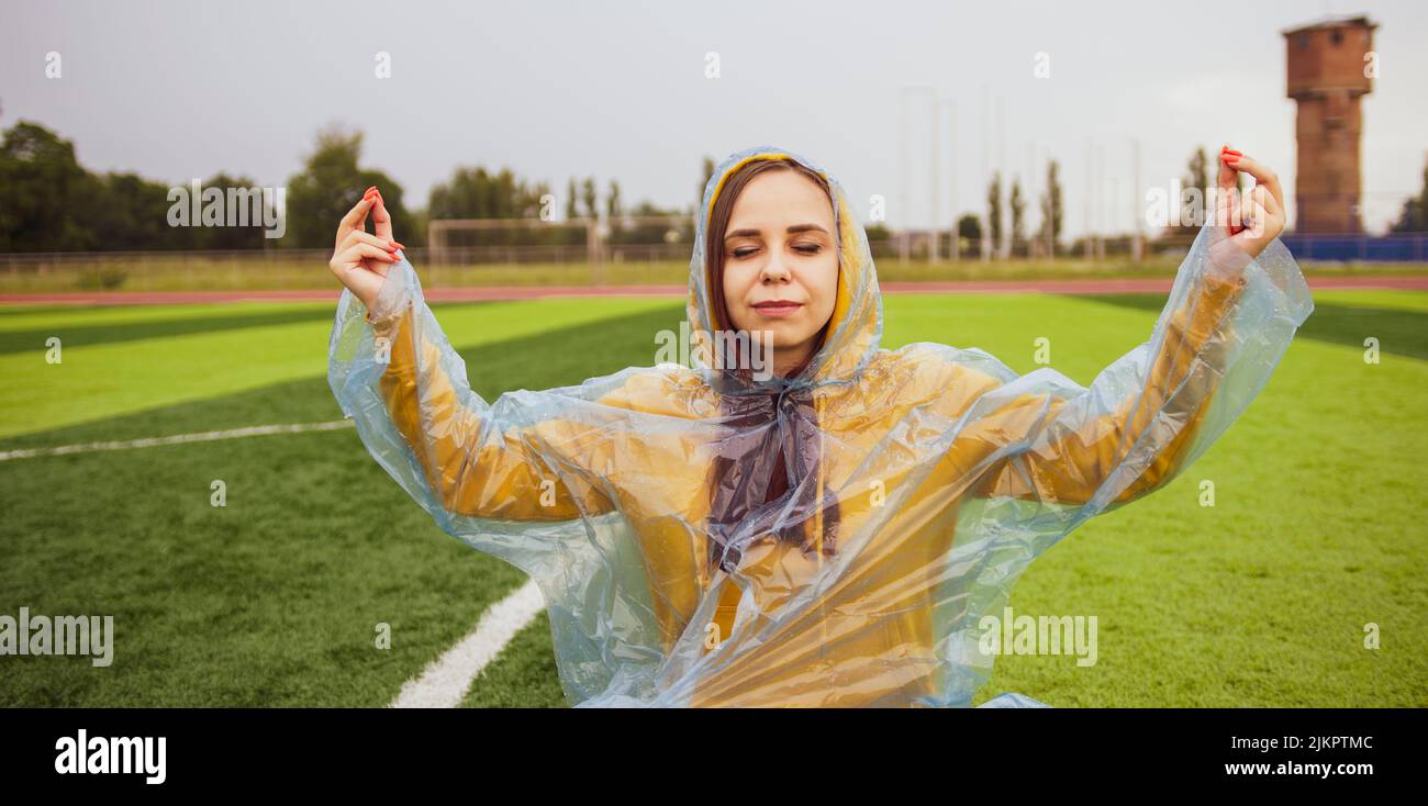 Mujer positiva meditando con los ojos cerrados en el campo deportivo Foto de stock