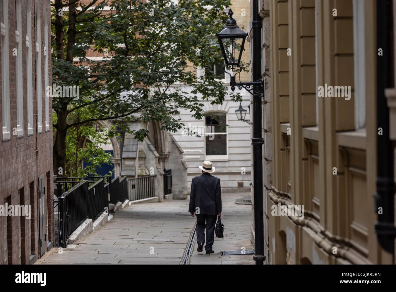 Hombre con un sombrero Trilby llevando su maletín camina por Temple Middle Lane, uno de los principales distritos legales de Londres y un notable centro de derecho. Foto de stock
