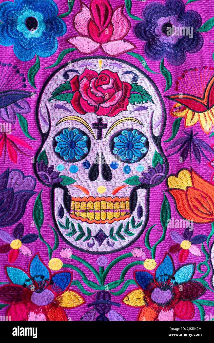 Bolso de mujer mexicana, hecho en Chiapas, con calavera y flores de varios colores, con fondo púrpura Foto de stock