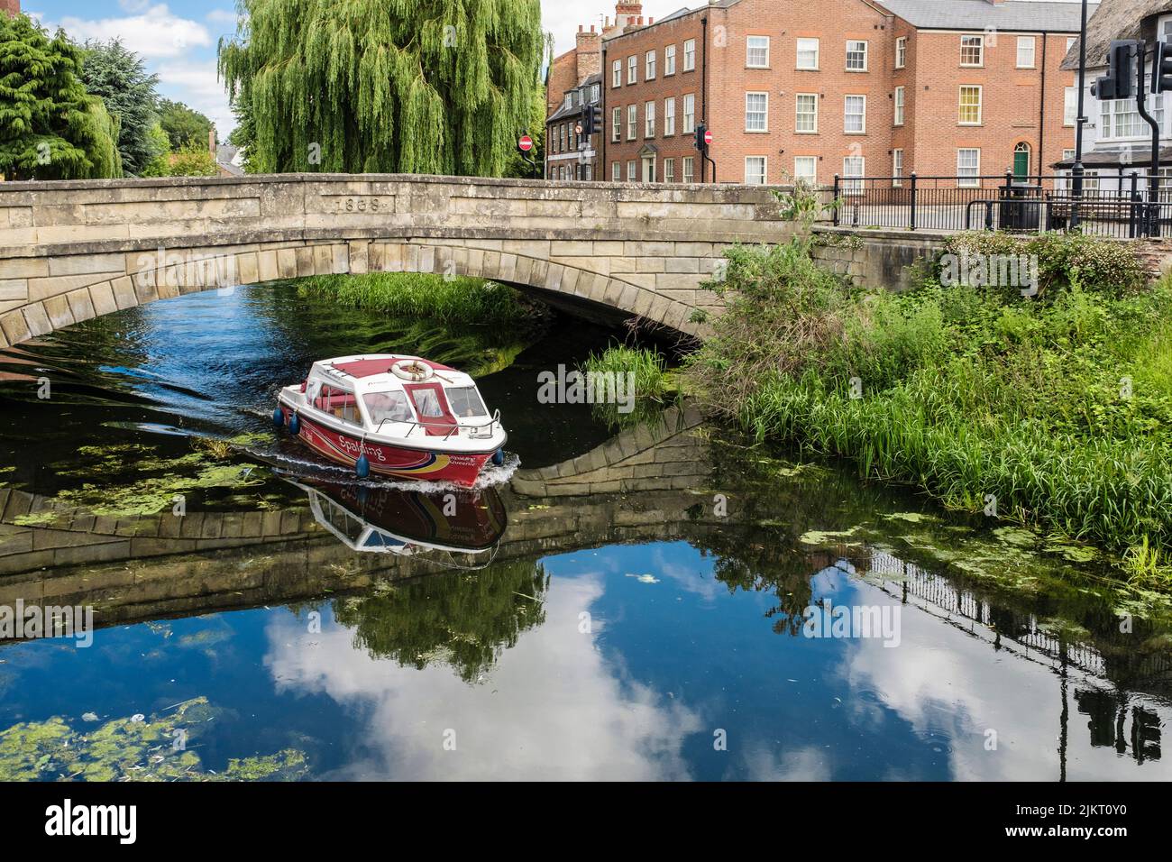 Un taxi acuático que pasa por debajo del viejo puente sobre el río Welland. Spalding, Lincolnshire, Inglaterra, Reino Unido, Gran Bretaña Foto de stock