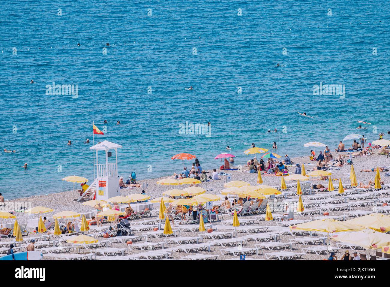 04 de junio de 2022, Antalya, Turquía: Playa de ciudad llena de gente con cientos de turistas y turistas descansando, tomando el sol y nadando en el verano extremadamente caliente d Foto de stock