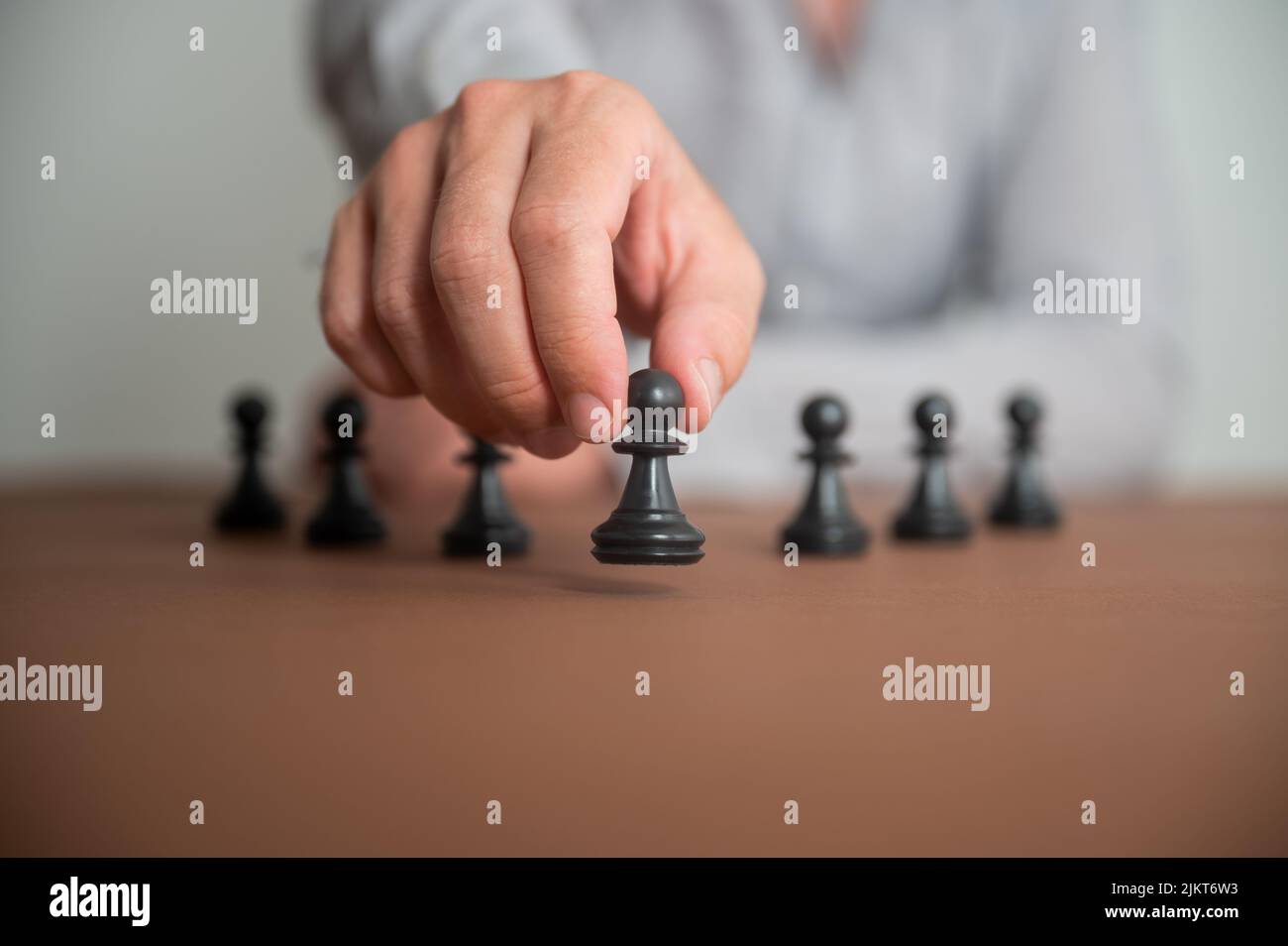 Vista de primer plano de la mano masculina caucásica moviendo una pieza de ajedrez de peón en una imagen conceptual de estrategia de negocios y tácticas. Foto de stock