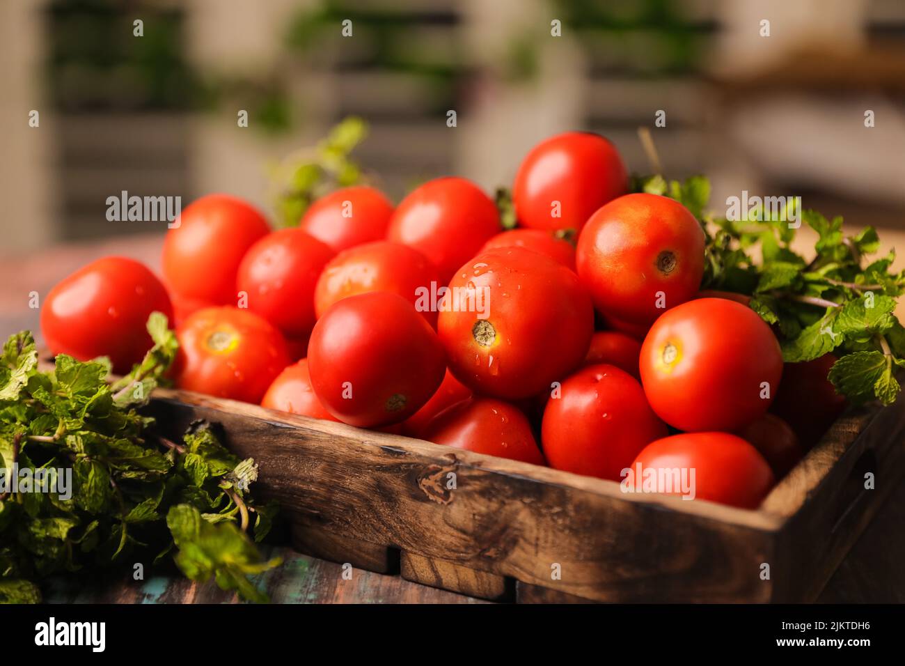 Un primer plano de tomates apilados en una caja de madera y verduras Foto de stock