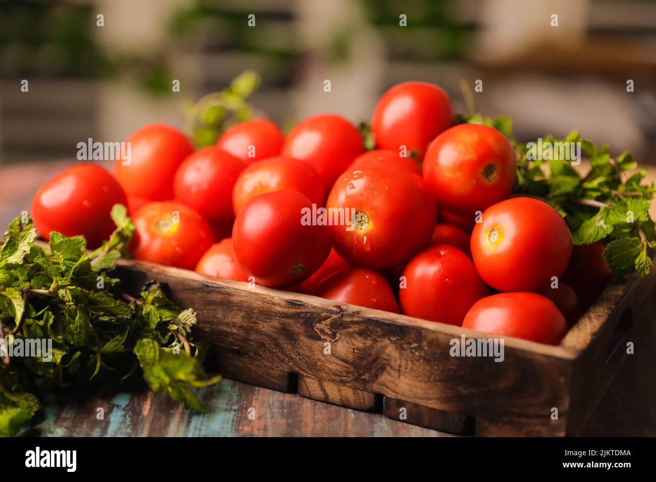 Un primer plano de tomates apilados en una caja de madera y verduras Foto de stock